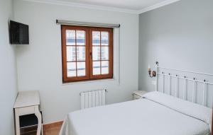 a white bedroom with two beds and a window at Casa Veiga in Valdoviño