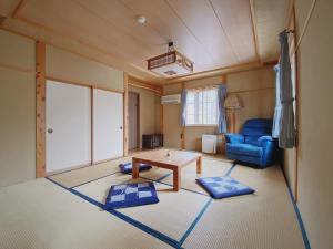 a living room with a table and a blue couch at Apricot Pension in Hakuba