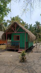 een groen huis met een rieten dak op een strand bij Hotel Las Casitas De Mar Adentro in Isla Grande