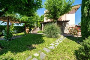a garden with a house and trees and grass at La Veranda - Appartamento con giardino privato in Ghizzano