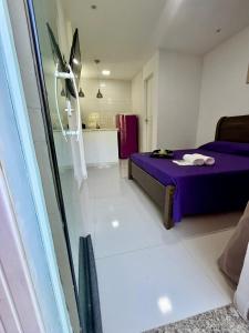 a bedroom with a purple bed and a bathroom at Flat Três Praias in Angra dos Reis