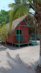 ein rotes Haus mit einem Strohdach am Strand in der Unterkunft Hotel Las Casitas De Mar Adentro in Isla Grande