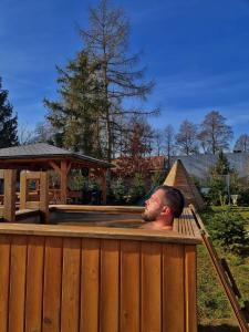 un hombre en un jacuzzi en un patio trasero en Domki w Dolinie Radomki, 