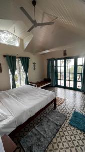 a bedroom with a large bed with a ceiling fan at KAAYAMKAAD - FOREST DWELLINGS COORG in Madikeri