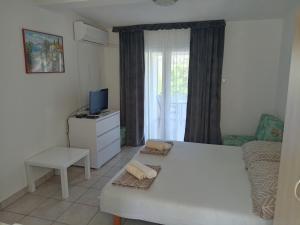 a living room with a white bed and a television at Apartments Šešo in Pag