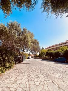 a cobblestone street with trees and cars on it at Il Maestrale in La Maddalena