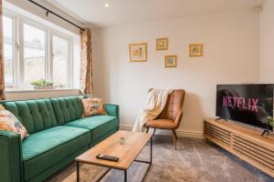 a living room with a green couch and a tv at Beautifully done 5 bed barn conversion in Heswall - Sleeps up to 10 in Heswall