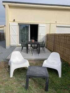 un patio con 3 sillas, una mesa y sillas en La Bagatelle 100 m de la plage en Hauteville-sur-Mer
