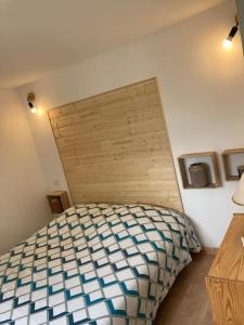 1 dormitorio con 1 cama con cabecero de madera en La Bagatelle 100 m de la plage en Hauteville-sur-Mer