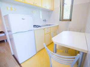 a kitchen with a white refrigerator and a table at Apartment and rooms Kristina in Baška