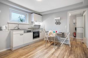kuchnia z białymi szafkami, stołem i krzesłami w obiekcie Rügenferienhaus Gartenwohnung w mieście Schaprode