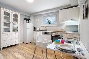 kuchnia z białymi szafkami, stołem i krzesłami w obiekcie Rügenferienhaus Gartenwohnung w mieście Schaprode +12 zdjęć