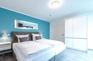 una camera con un grande letto con una parete blu di Tao-Suite mit Dachterrasse, Sauna und Kamin a Krakow am See