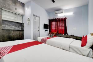 2 camas en una habitación con cortinas rojas en Flagship Sai International Near Nagasandra Metro Station en Bangalore