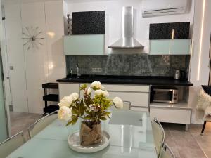 una cocina con una mesa de cristal con un jarrón de flores en PUERTO BANUS Apartamento DUO en Marbella