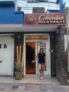 una mujer parada en la puerta de un restaurante en Hostal COLUMBIA, en Moquegua