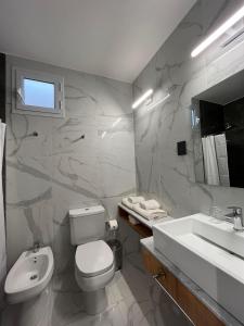 a bathroom with a white toilet and a sink at TERMAS PISMANTA Hotel & Spa in Las Flores
