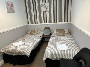 two twin beds in a room with a chair at Tuxford House in Blackpool