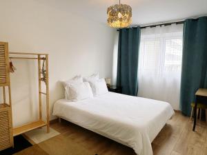 a bedroom with a white bed with blue curtains and a chandelier at Paradis de Vanves in Vanves
