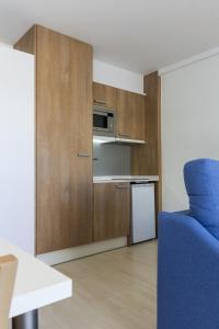 a small kitchen with a microwave and a blue chair at Acacias Apartamentos Salou in Salou