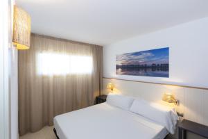 um quarto de hotel com uma cama branca e uma janela em Acacias Apartamentos Salou em Salou