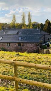 una casa en un campo detrás de una valla de madera en Dog friendly barn conversion in the Wye Valley en Mitchel Troy