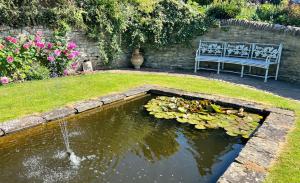 un estanque con un banco y una fuente de agua en Cider Mill Cottage, en Clifton upon Teme