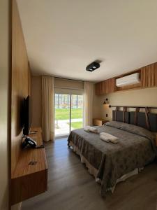 a bedroom with a bed and a television and a window at TERMAS PISMANTA Hotel & Spa in Las Flores