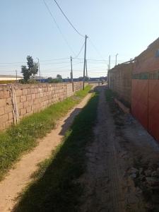 un camino de tierra junto a una pared de ladrillo en Casa Linda en Maputo