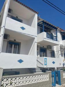 a white building with blue doors and windows at Pansion Katerina in Skala Eresou
