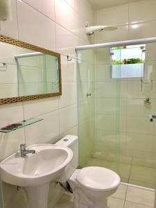 a bathroom with a sink and a toilet and a glass shower at Porto Paraty Residencial in Paraty