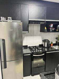 a kitchen with a stainless steel refrigerator and a stove at Quarto vip in Uberaba