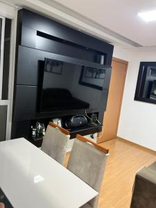 sala de estar con mesa y TV de pantalla plana grande en Quarto vip, en Uberaba