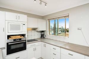 a white kitchen with white cabinets and a window at Sandcastles At The Beach Outstanding Location! in Perth