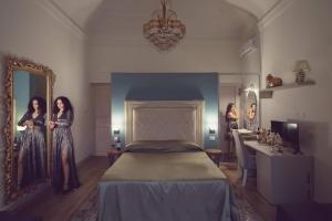 Dos mujeres de pie en un dormitorio con una cama en Kèramos Luxury Rooms, en Sciacca