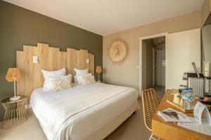Schlafzimmer mit einem großen weißen Bett und einem Schreibtisch in der Unterkunft Hôtel BO & MIA in La Baule