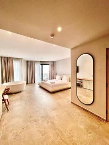 a bedroom with a large mirror and a bed and a tub at Andon Lapa Hotel & Spa in Sarandë
