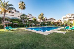 basen na dziedzińcu z palmami i budynkami w obiekcie 75-Apartment with Views in Elviria, Marbella w Marbelli