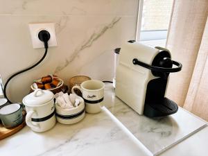 a coffee maker and cups on a counter at Paradis de Vanves in Vanves