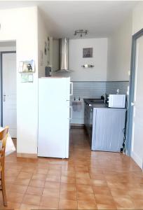 a kitchen with a white refrigerator and a wooden floor at Maison de 2 chambres avec wifi a Avesnes en Val in Avesnes-en-Val