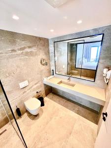 a bathroom with a toilet and a sink and a mirror at Andon Lapa Hotel & Spa in Sarandë