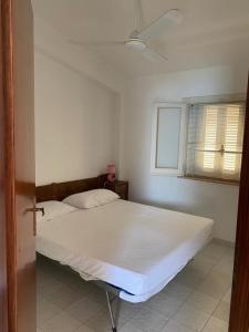 un letto bianco in una stanza con finestra di Cala Azzurra a Cittadella del Capo