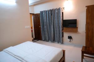 um quarto com uma cama e uma televisão de ecrã plano em HILL PALACE RESIDENCY COORG em Virajpet