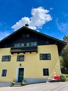 ein großes gelbes Haus mit schwarzem Dach in der Unterkunft Bauernhaus Stöcklhub in St. Johann im Pongau