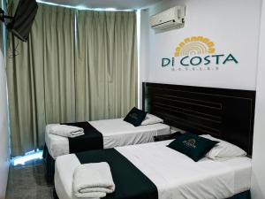 3 camas en una habitación de hotel con un cartel en la pared en Di Costa Hoteles, en Piura