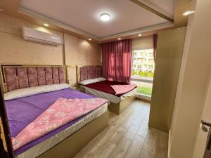 um pequeno quarto com 2 camas e uma janela em شاليهات مارينا دلتا ولاجونز em Al Ḩammād