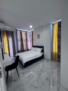 a bedroom with a bed and a chair and windows at Prime Luxury Apartments in Lushnjë