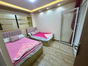 Duas camas num quarto com lençóis cor-de-rosa e um espelho em شاليهات مارينا دلتا ولاجونز em Al Ḩammād