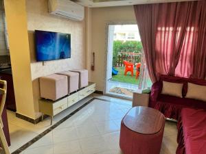 uma sala de estar com um sofá e uma televisão em شاليهات مارينا دلتا ولاجونز em Al Ḩammād