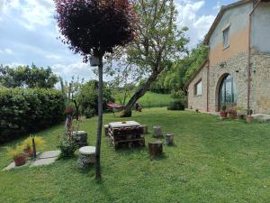 un jardín con una mesa y un árbol y un edificio en La Piccola fattoria en Todi